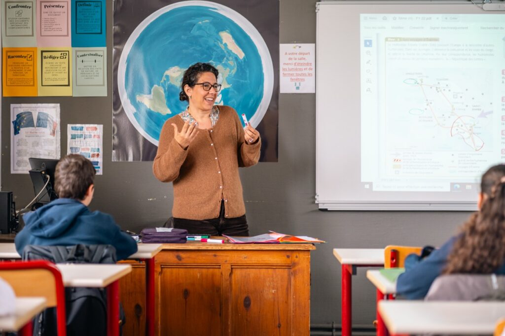 Une enseignante du collège Sainte-Thérèse devant une carte du monde, face à sa classe