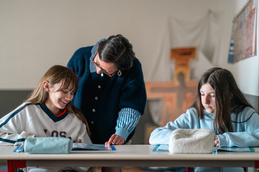 Une enseignante accompagne deux élèves à leur table de travail