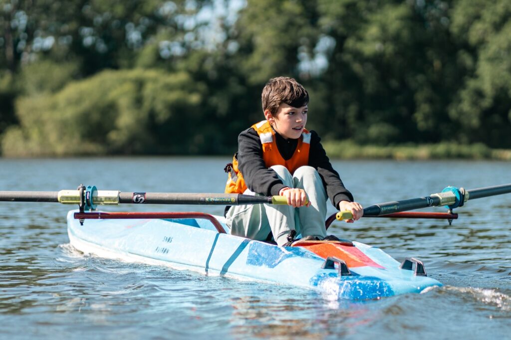 Un collégien rame en aviron sur le plan d'eau, activité nautique du collège