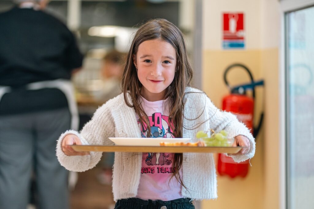 Une élève porte son plateau au restaurant scolaire de l'école